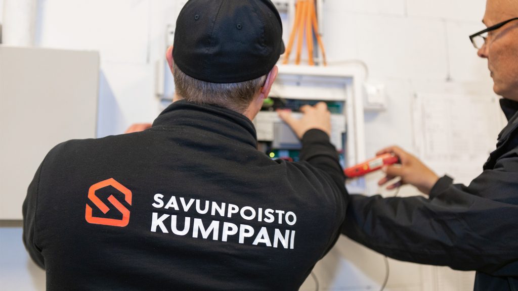 Savunpoistokumppanin huoltoteknikot huoltamassa savunpoistokeskusta. Keskuksesta mitataan mm. latausjännite ja varavoima-akuille tehdään kuormitustestaus.