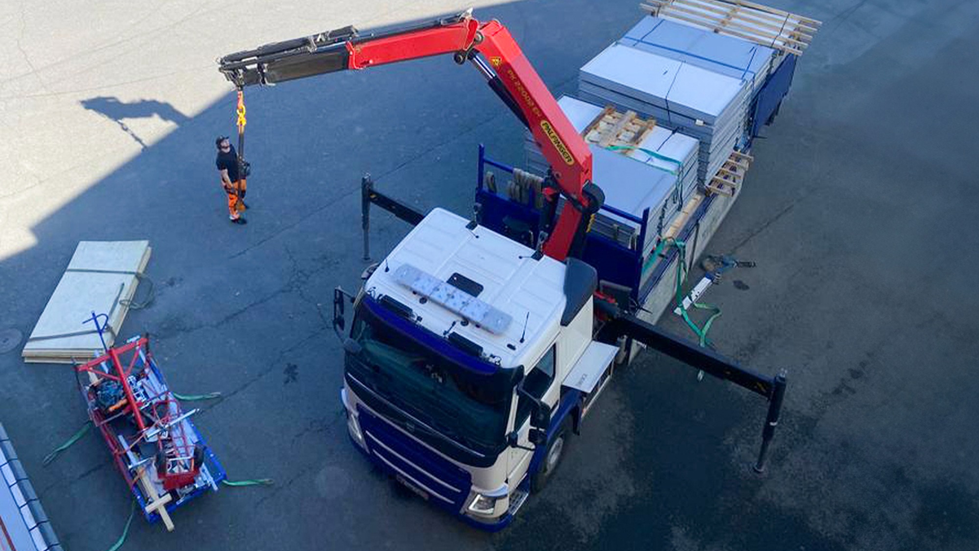 Savunpoistoluukkujen kansien vaihtoa. Nosturilla varustettu kuorma-auto nostamassa luukkujen kansia katolle. Luukkujen kannet ovat umpimallisia eli peltiverhoiltuja.